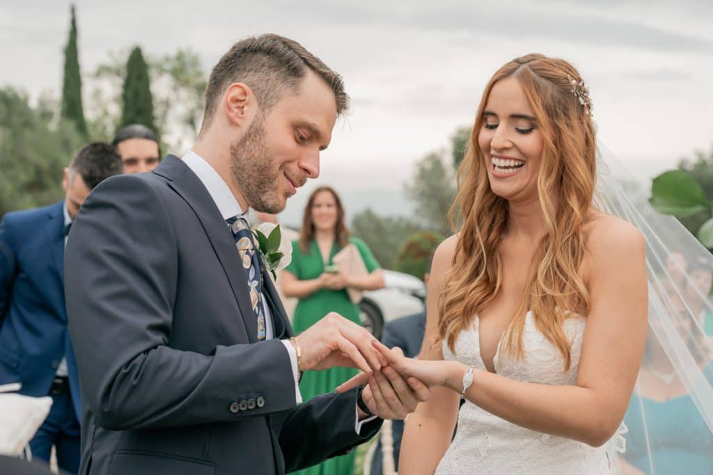 matrimonio vicino a Firenze - lo sposo mette ll'anello nuziale al dito della sposa mentre sorridono